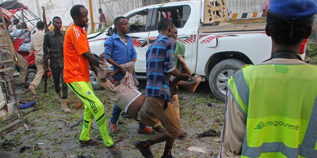 Somalis carry away the wounded civilian who was injured in a car bomb that was detonated in Mogadishu, Somalia, Saturday.