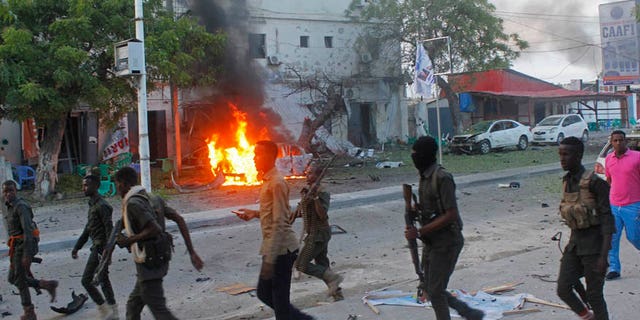 May 8, 2017: Somali security walk near a burning car after a car bomb attack on a restaurant in Mogadishu, Somalia.