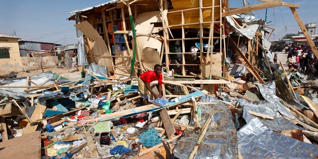 A shopkeeper surveys the wreckage of shops destroyed by a blast in a market in the capital Mogadishu, Somalia Sunday, Feb. 19, 2017. A Somali police officer says a blast at a busy market in the western part of Somalia's capital tore through shops and food stands and killed more than a dozen people and wounded many others. (AP Photo/Farah Abdi Warsameh)