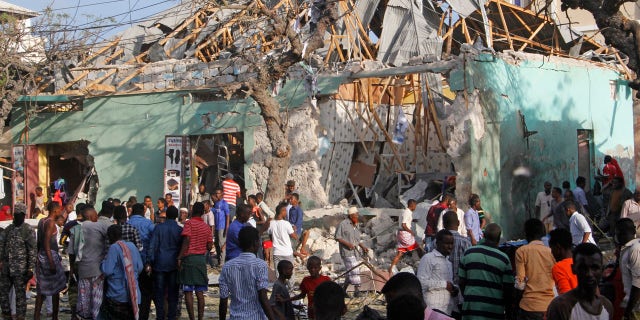 Somalis stand outside a destroyed building after a car bomb in Mogadishu, Somalia, March 22, 2018.