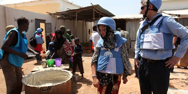 Jan 19, 2012: United Nations personnel look on as a worker serves food at a camp in Hodan district in Mogadishu. (Reuters)