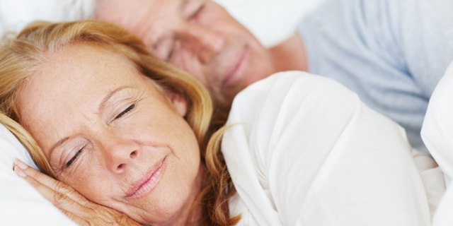 Attractive senior couple lying in bed together and sleeping