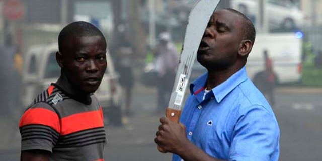 April 14, 2015: In this photo taken in Durban, South Africa, an immigrant armed with a machete on a street during clashes with police and in search of locals that attacked foreign shop owners in the city center.