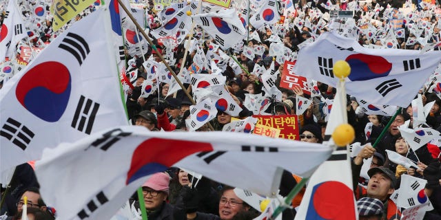Supporters of South Korean President Park Geun-hye wave their national flags during a rally opposing her impeachment in Seoul, South Korea, Saturday, Dec. 31, 2016.