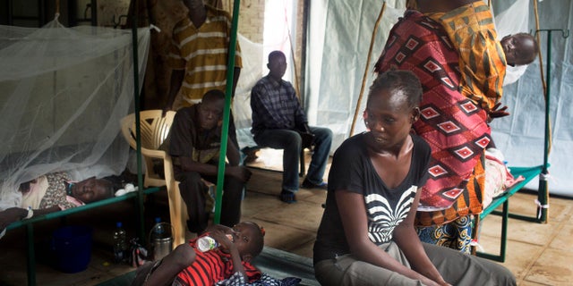 FILE--- In this Saturday May 24, 2014 file photo a South-Sudanese family waits in the cholera isolation ward of Juba Teaching Hospital in the capital Juba, South Sudan. UNICEF says 11 people have died in a suspected cholera outbreak in South Sudan. The organization said Tuesday there are 72 suspected cases so far, including 36 in the capital, Juba. Others are in Bor and Terekeka counties.(AP Photo/Matthew Abbott/file)