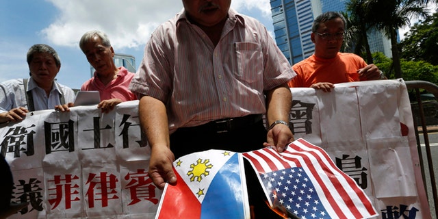 May 10, 2012: A protesters burns a Philippine flag and a U.S. flag during a protest outside the Philippines Consulate in Hong Kong.