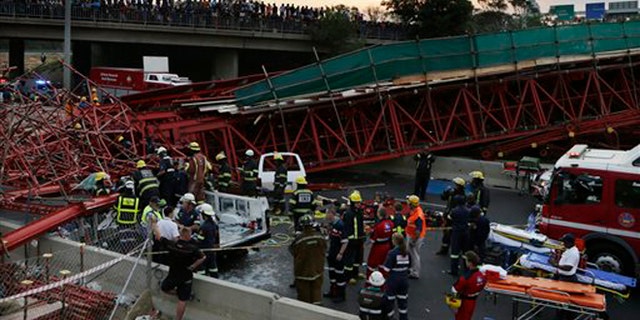 Oct. 14, 2015: Emergency service workers and paramedics help an injured man from a vehicle, which was partly crushed beneath scaffolding after a temporary bridge collapse in Johannesburg, South Africa.