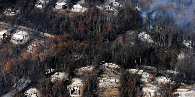 FILE - In this Tuesday, Nov. 29, 2016, file photo, smoke rises from destroyed homes, many burned down to the foundation, the day after a wildfire that hit Gatlinburg, Tenn. Experts said that escaping a fire-filled forest, as thousands did Nov. 28 in the Great Smoky Mountains, can be more traumatic than disasters such as hurricanes, floods or earthquakes. One reason: Flames that scorched neighborhoods in the Gatlinburg, Tenn., area spread so rapidly that people had no time to brace for it. (Paul Efird/Knoxville News Sentinel via AP, File)
