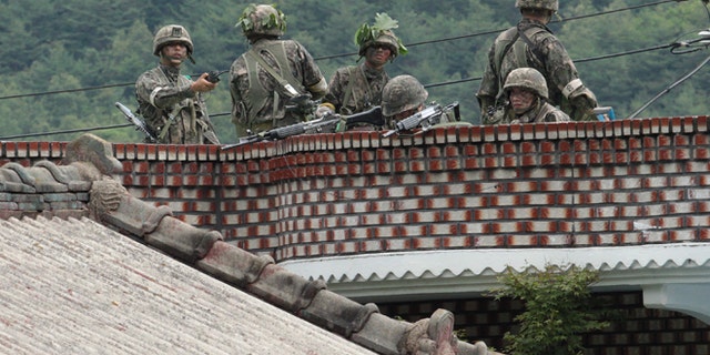 June 22, 2014: South Korean army soldiers take position on the roof of a private house to search for a South Korean conscript soldier who is on the run after a shooting incident in Goseong, South Korea. (AP)