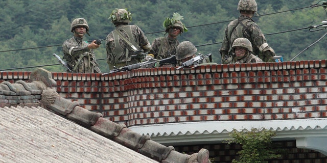 June 22, 2014: South Korean army soldiers take position on the roof of a private house to search for a South Korean conscript soldier who is on the run after a shooting incident in Goseong, South Korea. (AP)