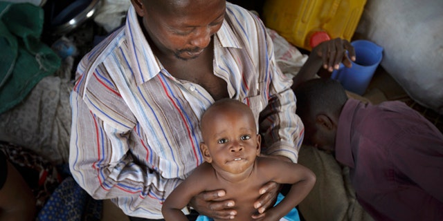 A displaced Ugandan boy is held by a relative as they wait for an evacuation flight from the United Nations camp. (AP/Ben Curtis)