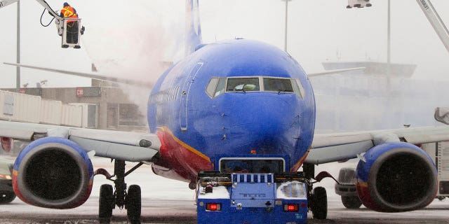 Southwest Airlines crew members are seen de-icing an aircraft at Boston's Logan International Airport in 2014. The airline recently confirmed that a lack of de-icing fluid was responsible for flight cancellations in Chicago on Sunday.