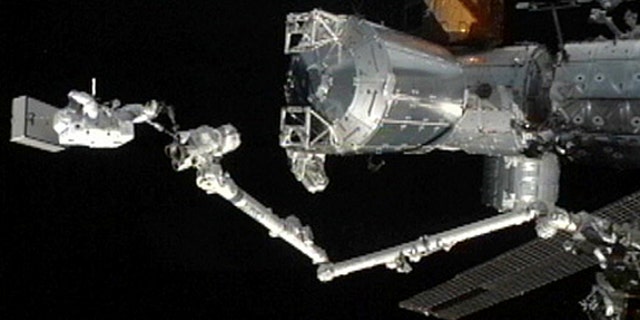 Japanese astronaut Akihiko Hoshides stands a the tip of the International Space Station's robotic arm during an Aug. 30, 2012, spacewalk outside the orbiting lab with crewmate Sunita Williams of NASA.
