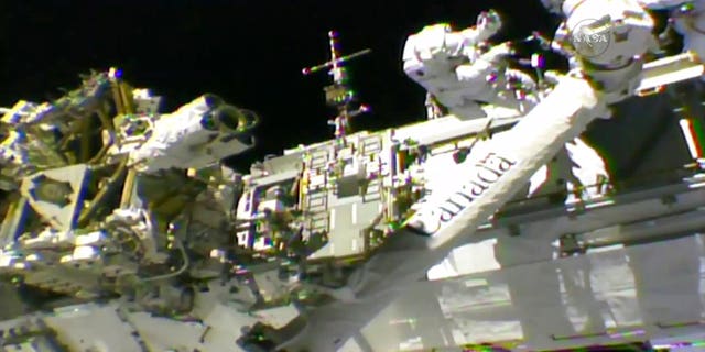 In this frame from NASA TV, Astronauts Mark Vande Hei, left, and Randy Bresnik work on the International Space Station on Thursday, Oct. 5, 2017. The astronauts went out on a spacewalk to give the International Space Station's big robot arm a new hand.