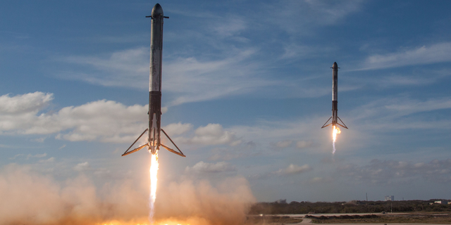 Two SpaceX Falcon Heavy boosters make a simultaneous landing after launching the first Falcon Heavy rocket into orbit on Feb. 6, 2018. Elon Musk says SpaceX will soon try to land the upper stage of its workhorse Falcon 9 rocket using a "giant party balloon."