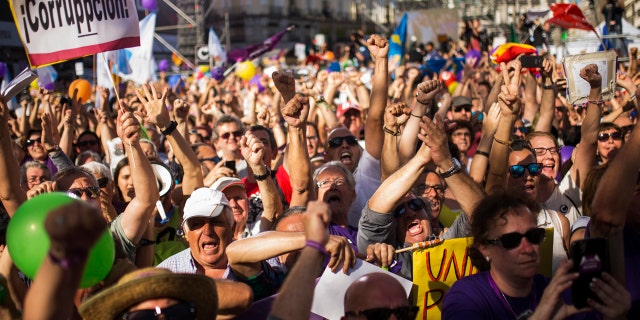 People, one holding a placard reading in Spanish: "Corruption", shout slogans during a rally in Madrid, Saturday, May 20, 2017.