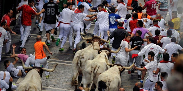 July 9, 2016: Revelers run with Jose Escolar Gil's fighting bulls as they head towards Estafeta street during the third running of the bulls at the San Fermin Festival, in Pamplona, Spain.