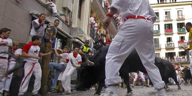 July 7, 2012: Revelers run on the Estafeta corner ahead of Dolores Aguirre Yabarra ranch bulls during the first running of the bulls at the San Fermin fiestas, in Pamplona northern Spain