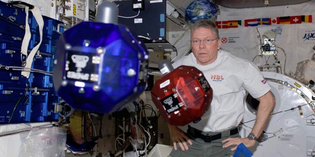 NASA Astronaut Mike Fossum operates small, autonomous satellites aboard the International Space Station in November 2011. Every year, high school students compete to submit computer code to run in the satellites, called SPHERES.