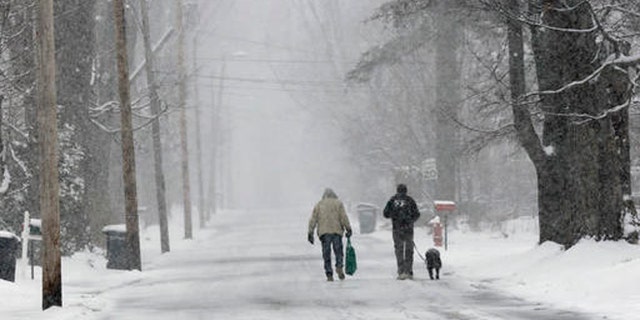 Bryan Gatneau, left, and David Baldwin, with his dog Winni walk home through the snow Tuesday, April 26, 2016, in Bethlehem, N.H.
