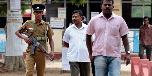 Sept. 8, 2012: A Sri Lankan police officer stands guard as ethnic Tamil voters leave a polling station after casting their votes in Batticaloa, Sri Lanka.