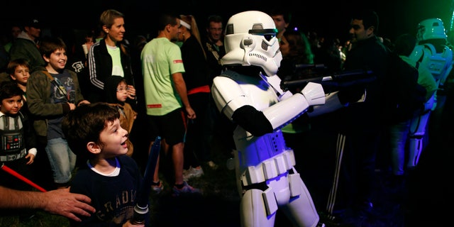 May 3, 2014. A boy looks at a man dressed as a stormtrooper from the Star Wars movies before the Star Wars Run race ahead of Star Wars Day in Buenos Aires.