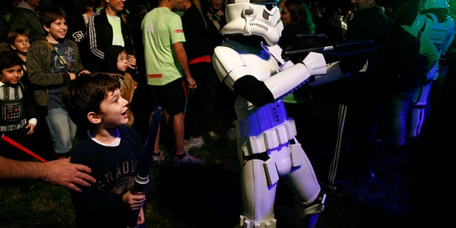 May 3, 2014. A boy looks at a man dressed as a stormtrooper from the Star Wars movies before the Star Wars Run race ahead of Star Wars Day in Buenos Aires.