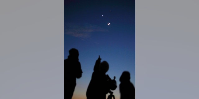 Star gazers look at the crescent moon below Jupiter (top) and Venus in Kathmandu December 1, 2008. (REUTERS/Gopal Chitrakar)
