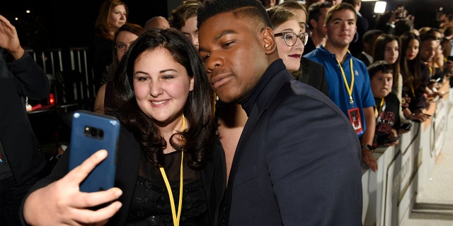 "Star Wars: The Last Jedi" cast member John Boyega poses for a photo with Olivia Sava, 14, of New York, at the premiere of the film at the Shrine Auditorium in Los Angeles.
