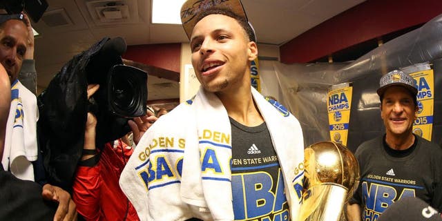 CLEVELAND, OH - JUNE 16: Stephen Curry #30 of the Golden State Warriors celebrates with the Larry O'Brien NBA Championship Trophy in the locker room after they defeated the Cleveland Cavaliers 105 to 97 in Game Six of the 2015 NBA Finals at Quicken Loans Arena on June 16, 2015 in Cleveland, Ohio. NOTE TO USER: User expressly acknowledges and agrees that, by downloading and or using this photograph, user is consenting to the terms and conditions of Getty Images License Agreement. (Photo by Ezra Shaw/Getty Images)