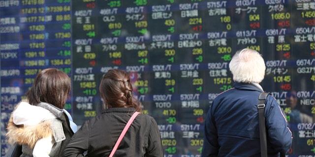 Pedestrian look at an electronic stock board of a securities firm in Tokyo, Tuesday, Nov. 1, 2016. Stocks indexes in Asia were mostly higher Tuesday after surveys showed China's factory activity rose to a two-year high last month, suggesting the world's No. 2 economy is stabilizing. (AP Photo/Eugene Hoshiko)