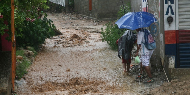 People walk under a downpour on a flooded street in Acapulco, Mexico, Thursday, Sept. 14, 2017.