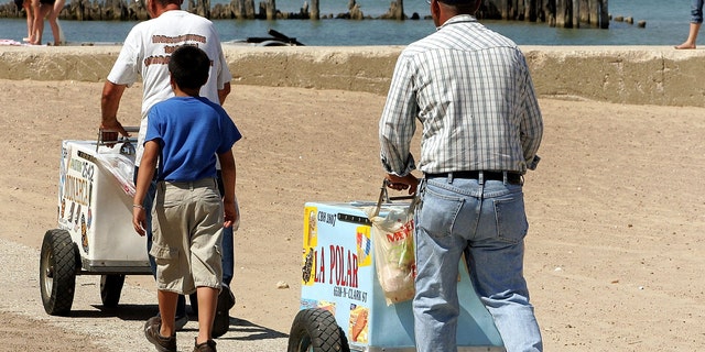 CHICAGO - JULY 24: Ice cream vendors push their carts on a beach along Lake Michigan July 24, 2005 in Chicago, Illinois. Extreme hot weather has hit several parts of the nation with highs over 100 degrees predicted in the Chicago area. (Photo by Tim Boyle/Getty Images)
