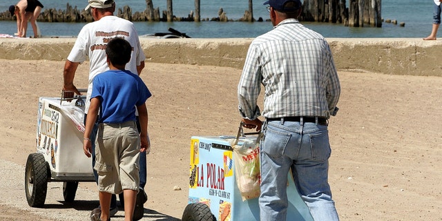 CHICAGO - JULY 24: Ice cream vendors push their carts on a beach along Lake Michigan July 24, 2005 in Chicago, Illinois. Extreme hot weather has hit several parts of the nation with highs over 100 degrees predicted in the Chicago area. (Photo by Tim Boyle/Getty Images)