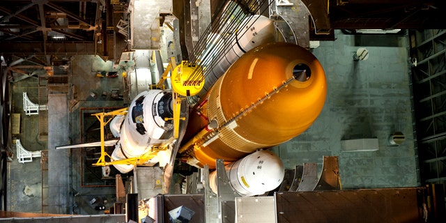 In the Vehicle Assembly Building at NASA's Kennedy Space Center in Florida, shuttle Endeavour is lowered into place where it is being attached to its external fuel tank and solid rocket boosters, already positioned on the mobile launcher platform. The shuttle is slated to launch its final mission STS-134 on April 19, 2011.