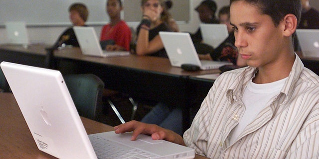 A student works with his Apple laptop in class at Empire High School in Vail, Ariz.