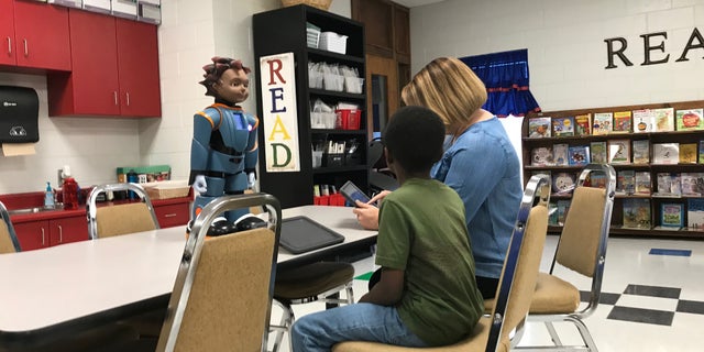 Facilitator Allison Thomlinson is using an iPad to prompt Milo if the student answered a question correctly or not. Williamston, SC.