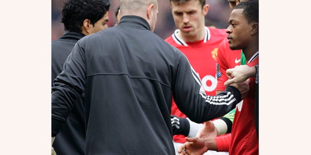 Manchester United's Patrice Evra, right, attempts to shake hands with Liverpool's Luis Suarez, left, during their English Premier League soccer match at Old Trafford Stadium, Manchester, England, Saturday, Feb. 11, 2012. Suarez refused to shake the hand of the Manchester United defender Evra, their first meeting since the Liverpool forward was banned for eight matches for racially abusing Evra in October 2011.(AP Photo/Jon Super)