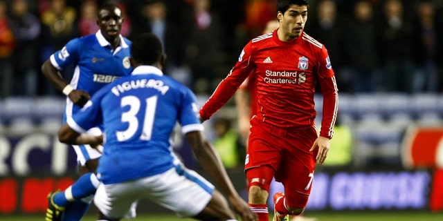 Liverpool's Luis Suarez, right, vies for the ball against Wigan's Maynor Figueroa, center, during their English Premier League soccer match at DW Stadium, Wigan, England, Wednesday Dec. 21, 2011. (AP Photo/Tim Hales)