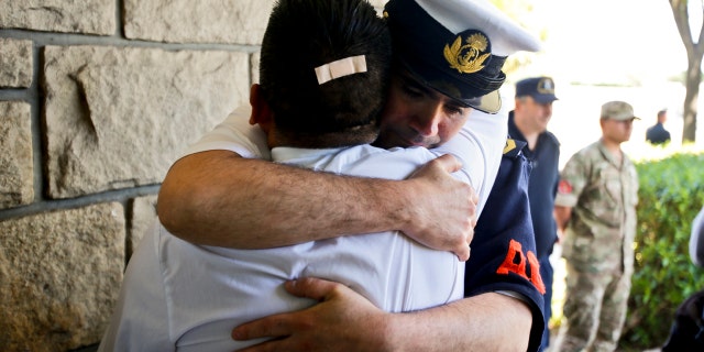 Argentine Navy officials embrace inside the Mar de Plata Naval Base after Argentina's Navy announced that a sound detected during the search for the missing ARA San Juan submarine is consistent with that of an explosion, in Mar de Plata, Argentina, Thursday, Nov. 23, 2017.