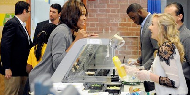 January 23, 2014: Famous Fans Justin Tuck, second from right, and Nastia Liukin, right, work behind the counter to serve up Fresh Fit sandwiches to First Lady Michelle Obama.