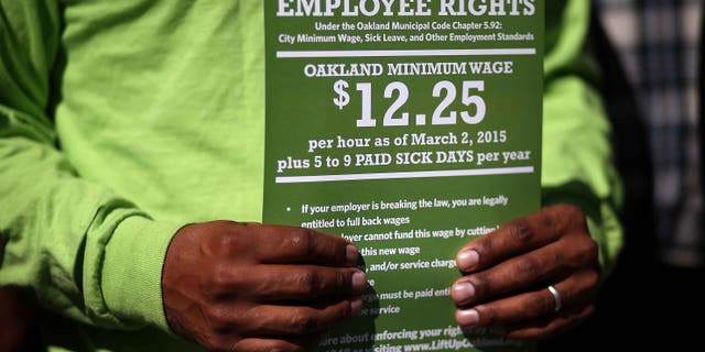 OAKLAND, CA - FEBRUARY 27: A supporter of Oakland's minimum wage increase holds a sign during a celebration rally outside of Oakland City Hall on February 27, 2015 in Oakland, California. Dozens of minimum wage workers gathered on the steps of Oakland City Hall to celebrate a $3 increase in the city's minimum wage to $12.25 an hour. Voters passed measure FF in November with 81 percent voting in favor of the wage increase. The new wage goes into effect on March 2. (Photo by Justin Sullivan/Getty Images)