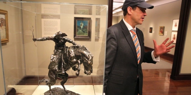 January 29, 2014: Denver Art Museum director Christoph Heinrich poses next to a Frederic Remington bronze of a cowboy riding a bucking horse, part of the museum's collection. The Denver and Seattle Art Museums have started a friendly wager: if the Broncos win the Super Bowl against the Seahawks, Seattle will send a Seahawk mask to Denver for three months. If the Seahawks win, Denver sends the Remington statue to Seattle for three months. (Brennan Linsley/Associated Press)