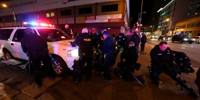 Denver police officers don gas masks and riot gear as they prepare to move back Broncos fans celebrating Denver's win in the Super Bowl.