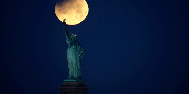 The Statue of Liberty is backdropped by a supermoon, Wednesday, Jan. 31, 2018, seen from the Brooklyn borough of New York. (AP Photo/Julio Cortez)
