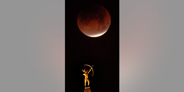 The eclipsing blood moon appears above the statue of Kansa Warrior Ad Astra atop the Kansas Statehouse in Topeka, Kan., Wednesday, Jan. 31, 2018. (AP Photo/Orlin Wagner)