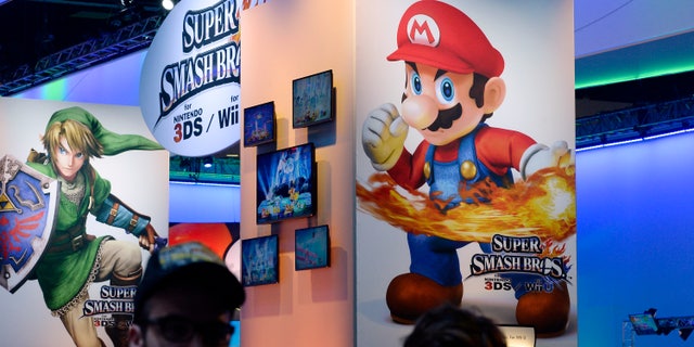 Attendees walk past Nintendo Co.'s Super Smash Bros. signage at the 2014 Electronic Entertainment Expo, known as E3, in Los Angeles, California June 11, 2014.