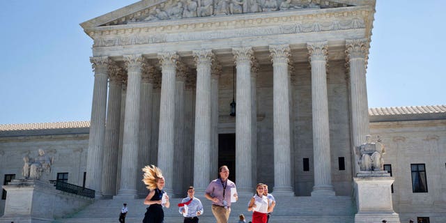 New interns run with a decision across the plaza of the Supreme Court in Washington, Monday June 29, 2015. On Monday, the court upheld Arizona congressional districts drawn by an independent commission and rejected a constitutional challenge from Republican lawmakers and upheld the use of a controversial drug in lethal injection executions Monday, as two dissenting justices said for the first time that they think it's "highly likely" that the death penalty itself is unconstitutional. (AP Photo/Jacquelyn Martin)