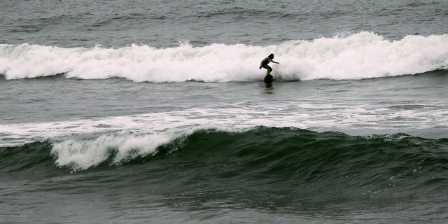 Surfer Joao Demacedo rides a wave at Martin's Beach, a popular surfing and fishing spot, in Half Moon Bay, California.