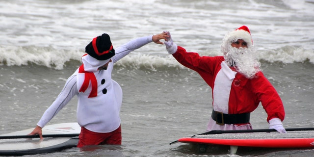 Dec. 24, 2013: George Trosset Jr., dressed as a snowman, left, and his dad, event organizer George Trosset, high-five each other out in the waves during the fourth annual "surfing Santas" event in Cocoa Beach, Fla.